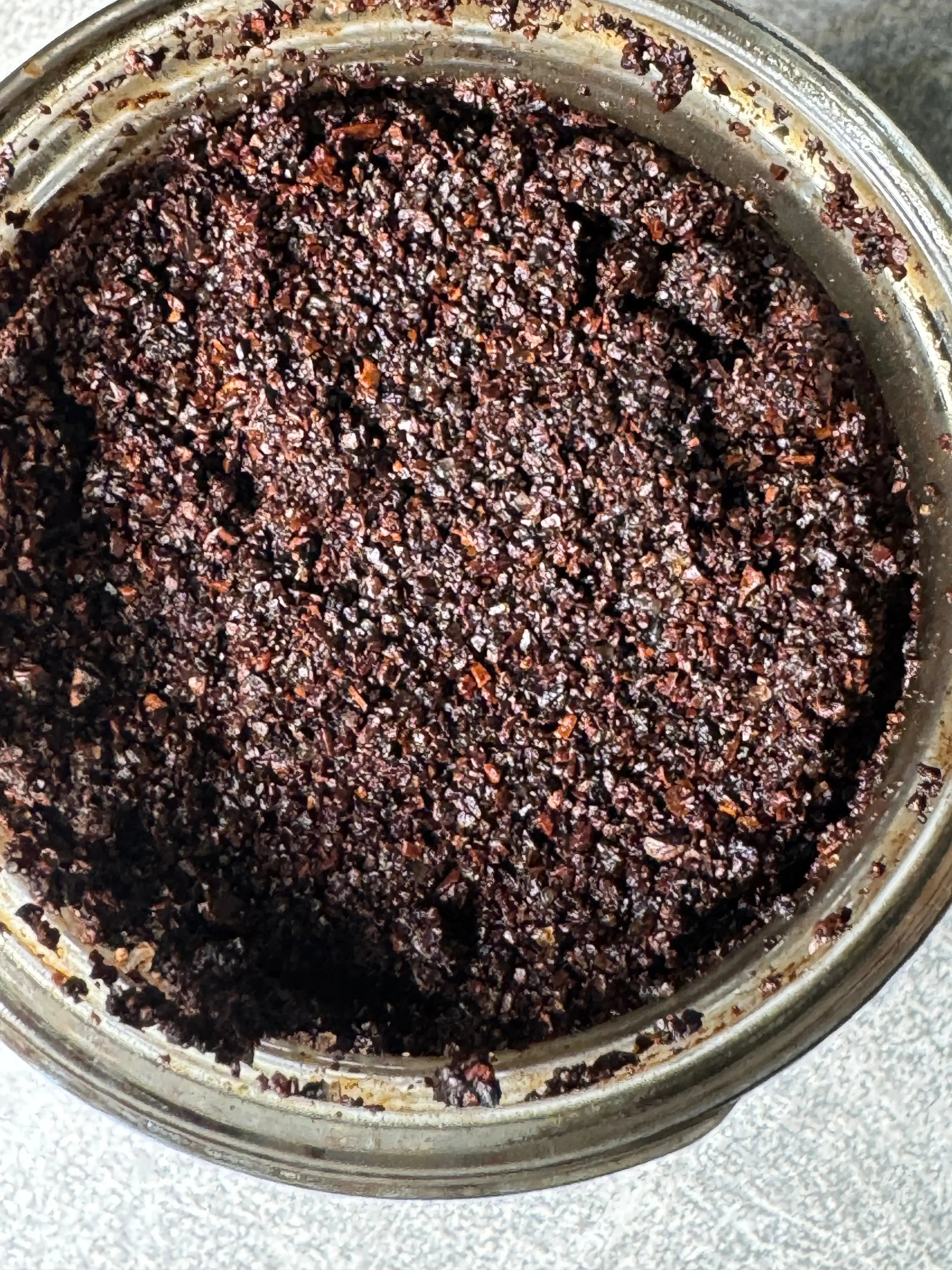 Close-up of Xquisit Luxe ground coffee scrub  in a glass jar on a gray surface